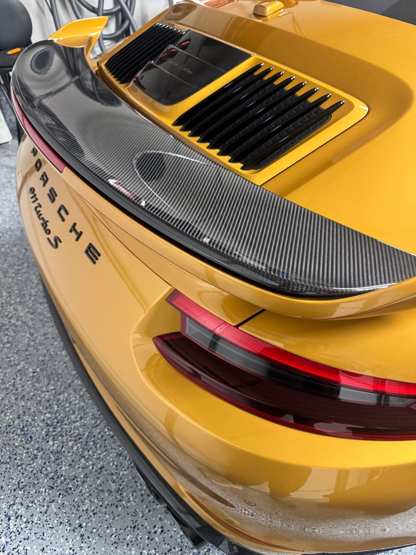 Close-up of a gold Porsche 911 Turbo S rear wing and taillight after detailing