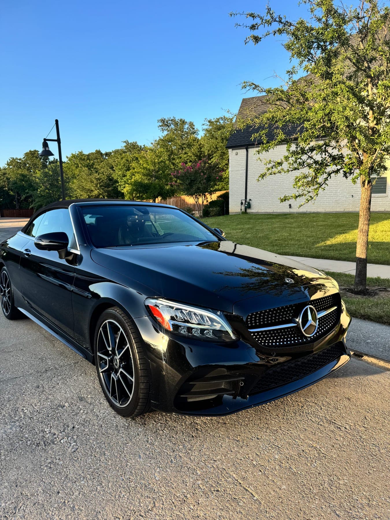 A detailed black Mercedes-Benz C-Class Cabriolet, front three-quarter view at dusk