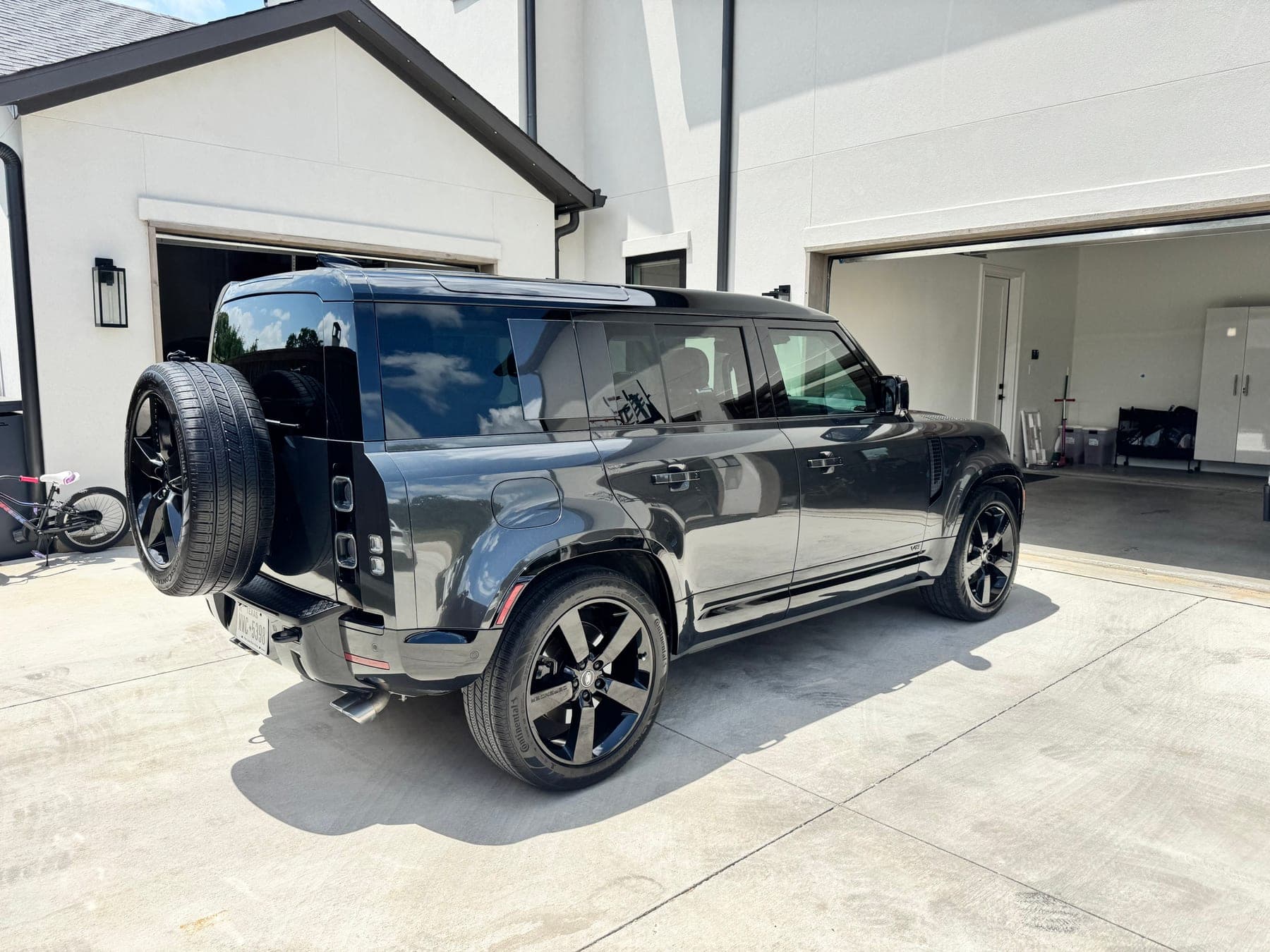 A detailed black Land Rover Defender, rear three-quarter view outside a home